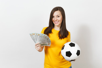 European young fun woman, football fan or player in yellow uniform holding bunch of money banknotes, soccer ball isolated on white background. Sport, play football game, excitement lifestyle concept.
