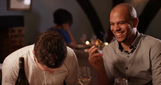 4K 2 Men laughing & enjoying a meal out, man offers his friend a taste of his meal