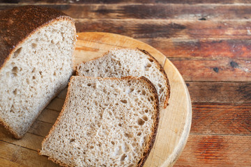 Freshly baked sliced bread on a wooden  cutting Board on old wooden rustic table.