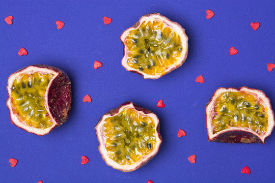 Sliced passion fruits on a dark blue background with sugar hearts.