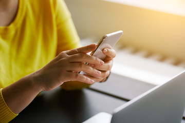 Woman with mobile phone and laptop in office