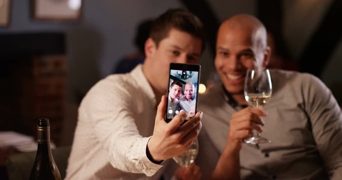 4K Close male friends or non-scene gay couple pose to take a selfie on night out in bar