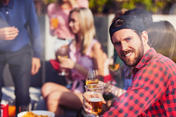 Young bearded man drinking beer with his friends