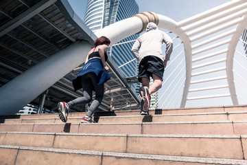 Young runners running on city bridge, Sporty couple jogging at morning with Bangkok urban scene background