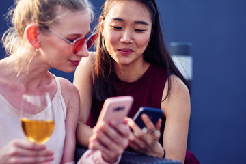Fototapeta premium Cheerful female friends using their smartphones
