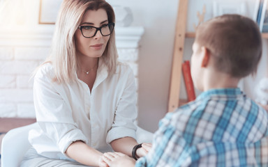 Fototapeta premium Believe me. Cheerful lady smiling while looking at a teenage kid and trying to establish contact and trust with a young patient.