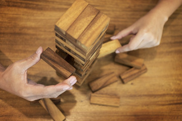 Business man placing wooden block on a tower concept of risk control planning risk and strategy.