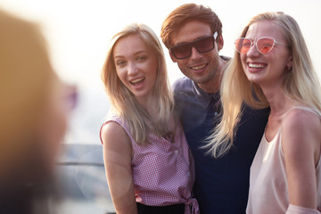 Cheerful guy resting with the smiling girls on the rooftop