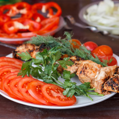 In a white plate are fresh vegetables with meat cooked on the grill.