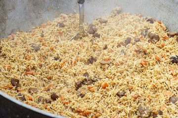 A traditional dish of Asian cuisine. Pilaf with beef, carrots, onions, garlic, pepper and cumin cooked outdoors.