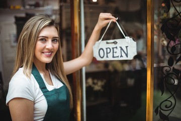 Female florist holding open signboard