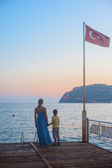 Fototapeta na wymiar mother and son on the pier in the evening at Alania, Turkey