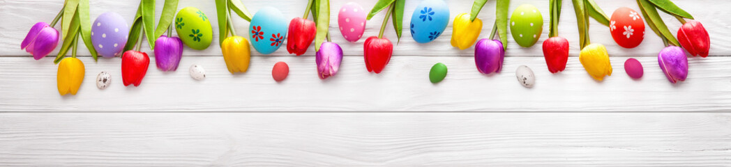 Easter Colored Eggs with Flowers on White Wood Background