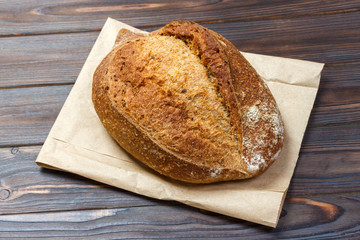 Loafs of fresh bread on wood background with paper bag. Top view