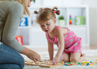 Kid girl playing with developmental toys in daycare center or kindergarten