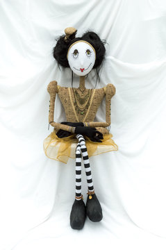 Creepy steampunk rag doll sitting facing forward. Legs crossed. Lifesize doll on a grungy white background. Part of a series of different poses. Vertical.