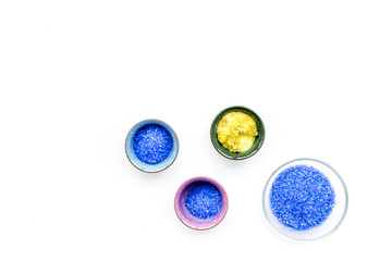 Colorful spa salt. Yellow spa salt with delicate spring flowers and violet lavender spa salt on white background top view copy space