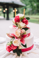 Beautiful wedding cake decorated with flowers and ribbons on white table