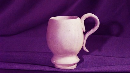 Mug out of clay on a purple background.