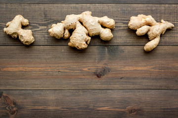 Whole ginger roots on dark wooden background top view space for text