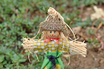 A scarecrow figurine standing in a garden