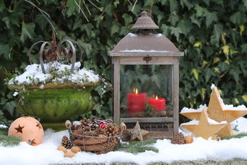 Gartendekoration im Winter mit Kerzen und Zapfen