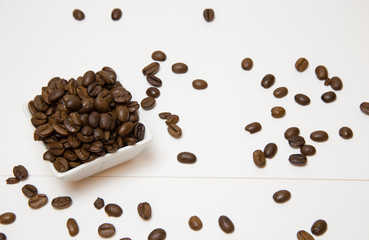 Coffee bean in small white ceramic dish on white background