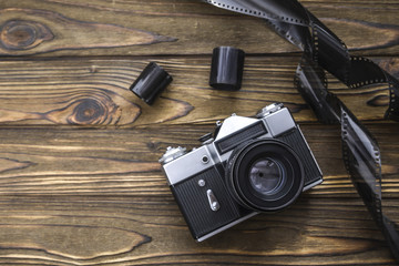 old camera with photographic film on a wooden background.