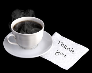 thank you on a napkin on a wooden table with a cup of coffee. Message written on napkin. Isolated on a black background