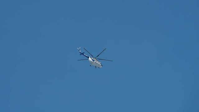 Russia's Helicopter MI-8 flying in the blue sky. Air transport helicopter with spinning blades.