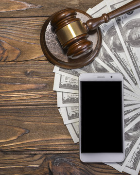 Gavel, hammer of the judge, smartphone screen black mockup, dollars on the background of a wooden table. lawyer. court. justice. offense and punishment. copy space