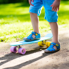 Child riding skateboard in summer park