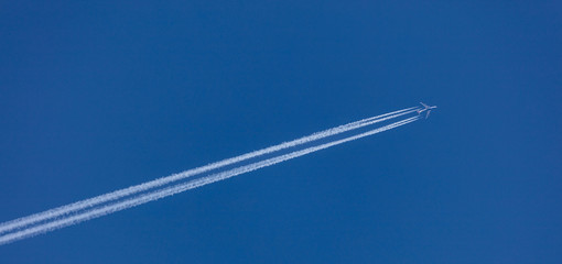 Plane with white trace behind it. Blue sky background, banner, under view, space for text.
