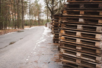 Wooden material pallets near industrial plant on the road