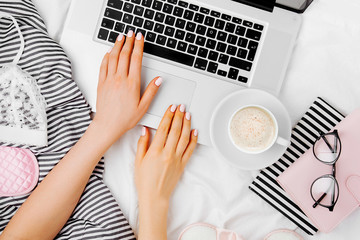 Fashion blogger working with laptop in bed, flat lay,  top view