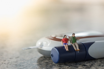 Fat man and woman miniature figure sitting on lancet with Glucose meter for check blood sugar level...