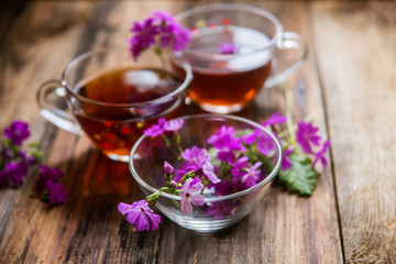 Bouquet of red tulips and cup of tea against a dark background. Festive flower background by a Mother's Day or other celebration.