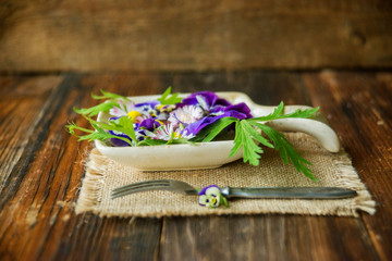 Sunflower sprouts, cucumber and edible flowers salad on wooden bowl