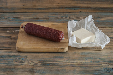 cheeses and sausage on wooden aged background.