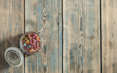 colorful sugar candy in glass jar on wooden table. Top view