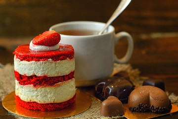 cake with strawberries, biscuits and a Cup of tea on a wooden table