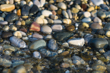 pebble stones on the sea beach, the rolling waves of the sea with foam