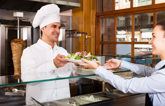 Ordinary waitress receiving order from chef