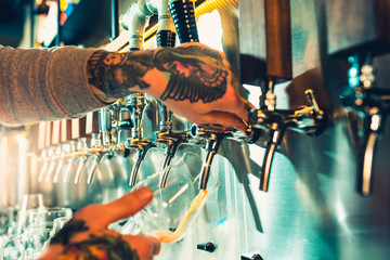 Obraz premium Ręka barmana nalewająca duże piwo jasne z beczki.