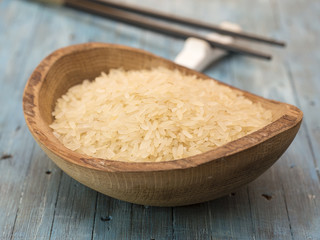 Rice in a wooden plate on a blue background. 