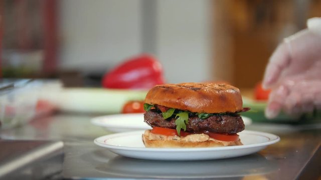 Chef serves a burger by adding potato chips on a plate