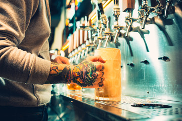 Hand of bartender pouring a large lager beer in tap.