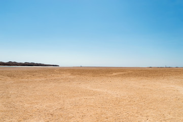deserted seashore, with yachts and a lighthouse in the background, against a blue sky background