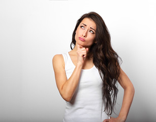 Confusion grimacing brunette woman thinking and looking up in white t-shirt on white copy space background