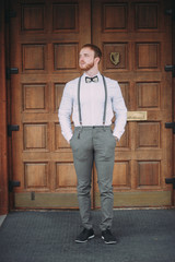 stylish groom in a white shirt and suspenders with a red beard
